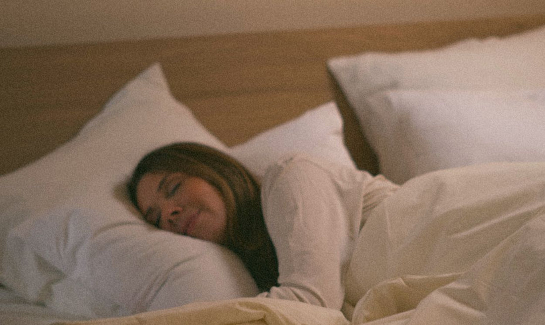 Femme endormie paisiblement dans un lit Kipli avec oreillers et linge de lit en matières naturelles.