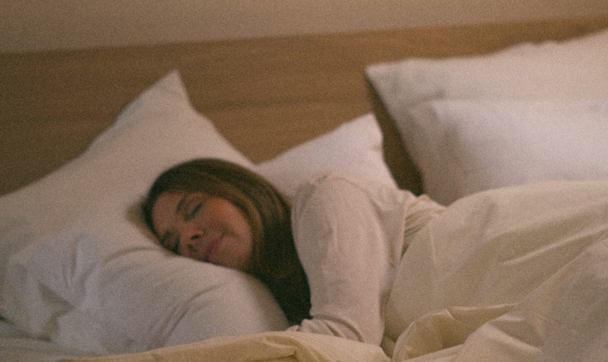 Eine Frau schläft friedlich in einem Kipli-Bett mit Kissen und Bettwäsche aus natürlichen Materialien.