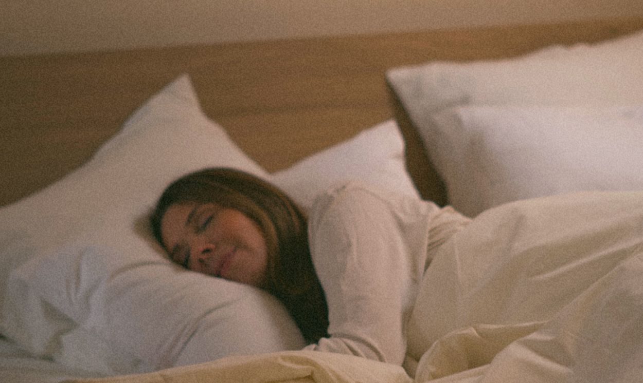 Eine Frau schläft friedlich in einem Kipli-Bett mit Kissen und Bettwäsche aus Naturmaterialien.