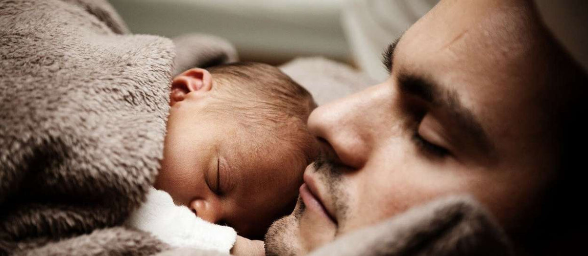 Papa, der neben dem Neugeborenen schläft, eingehüllt in eine weiche Decke